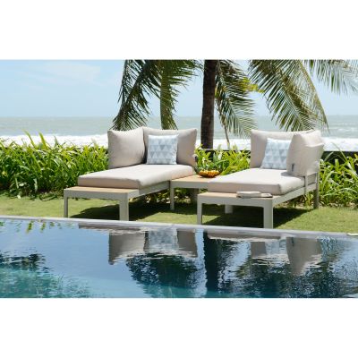Garten Loungegruppe mit zwei Sofa Elementen und Ablage auf einer Rasenfläche am Pool mit Palmen im Hintergrund