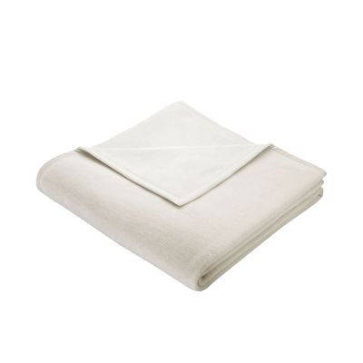 Gefaltete Wohndecke Cotton Home Natur in Cremeweiß mit schmal eingefasster Kante auf weißem Hintergrund.