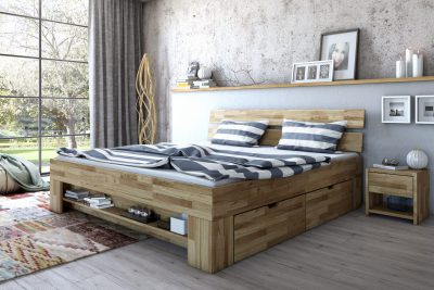 Ein Holzbett von Massivholzmöbel mit gestreifter Bettwäsche verschönert das sonnendurchflutete Schlafzimmer mit Teppich, Nachttisch und Blick ins Grüne.