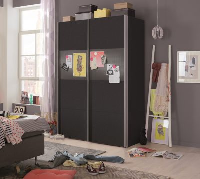 Sonnenlicht strömt in ein Schlafzimmer mit einem Schwebetürenschrank mit magnetischer Front, einem vollgestopften Boden und einem schiefen Leiterregal.