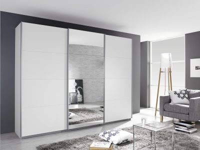 Modernes Wohnzimmer von Möbel Gruber mit Schwebetürenschrank, grauem Sofa, geometrischen Kissen, Stehlampe und Kunst.