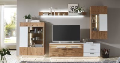 Modernes Wohnzimmer von Möbel Gruber mit einer „Wohnkombination“ inklusive TV-Möbel aus Holz, Regalen, Pflanzen und Kunst an einer grauen Wand.