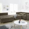Ein modernes Wohnzimmer von Möbel Gruber verfügt über eine Wohnlandschaft, einen runden weißen Tisch und geometrische Wandkunst.