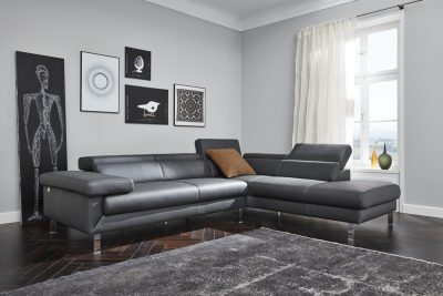 Modernes Wohnzimmer von Möbel Gruber mit schwarzem Ledersofa von W.SCHILLIG, geometrischer Kunst, transparenten Vorhängen und grauem Teppich.