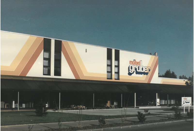 Das Möbel Gruber-Geschäft verfügt über eine Fassade mit geometrischen Mustern in leuchtenden Gelb- und Orangetönen.