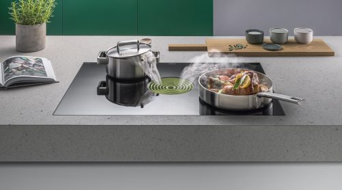 Moderne Küche von Möbel Gruber mit Induktionskochfeld. Töpfe und Pfannen im Einsatz, Schneidebrett und frische Kräuter im Blick.
