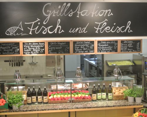 Eine Buffettheke von Möbel Gruber präsentiert Fisch, Fleisch und frische Produkte wie Tomaten und Zitronen auf einer Granitoberfläche.