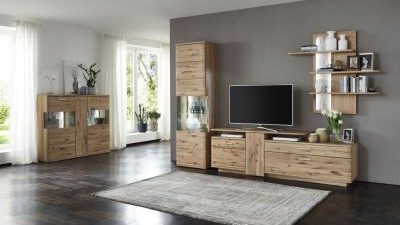Modernes Wohnzimmer mit Holzmöbeln, einem Fernseher, weißen Vasen und einem großen Teppich. Sonnenlicht fällt durch transparente Vorhänge.