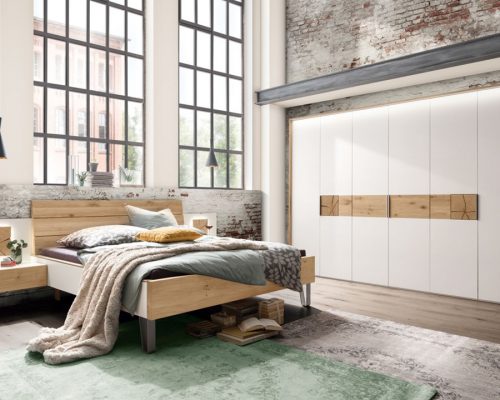 Schlafzimmer im Loft-Stil mit großen Fenstern, einem Holzbett, strukturierten Ziegelwänden, einem Kleiderschrank und einem grünen Teppich.