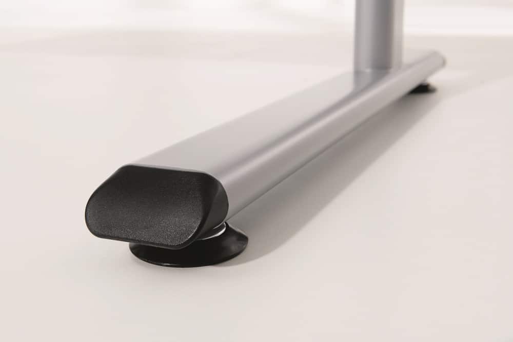 Nahaufnahme eines metallischen Möbelbeins von Möbel Gruber mit einer schwarzen Kappe auf einer glatten, hellen Oberfläche.