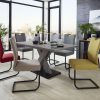 Modernes Esszimmer mit großem Esszimmertisch, bunten Stühlen und Blick auf die Stadt durch raumhohe Fenster.