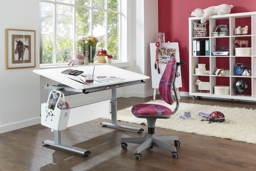 Kreativer Arbeitsplatz mit höhenverstellbarem Zeichentisch, buntem Stuhl von Möbel Gruber und Regal mit Spielsachen und Büchern in einem hellen Raum.