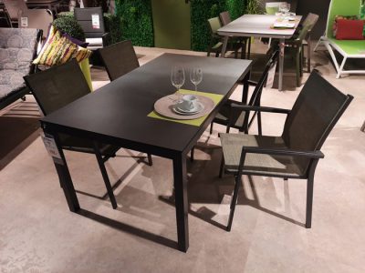 Eine moderne Terrassen-Essgruppe von Möbel Gruber mit einem schwarzen Tisch und zwei Stühlen, elegant präsentiert mit Gläsern und einem Teller.