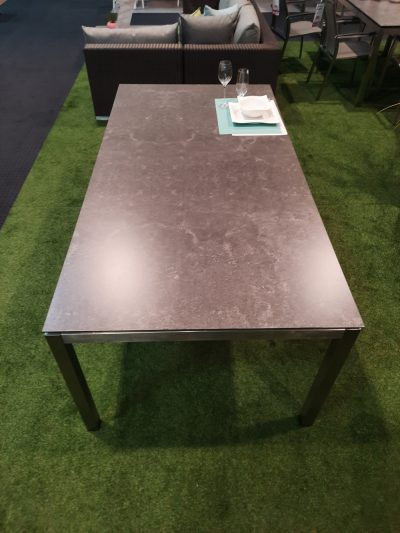 Tisch von Möbel Gruber auf grünem Teppich, mit steinähnlicher Oberfläche mit Tellern und Gläsern.