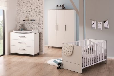 Modernes Kinderzimmer mit weißem Kinderbett, Kommode und Kleiderschrank von Paidi Babyzimmer, gepunktetem Dekor, hellem Holzboden, sanfter Beleuchtung.
