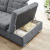 Graues Sofa von Möbel Gruber mit verstecktem Staufach, das den Blick auf Decken und Kissen neben einer Topfpflanze freigibt.
