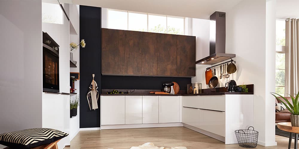 Moderne Küche mit weißen Schränken, dunklen Holzakzenten und Geräten aus Edelstahl. Helles Fensterlicht erfüllt den Raum.