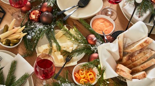 Festlich gedeckter Tisch von Möbel Gruber mit Rotwein, Käse, Baguettescheiben, Dip-Saucen und Dekogrün.