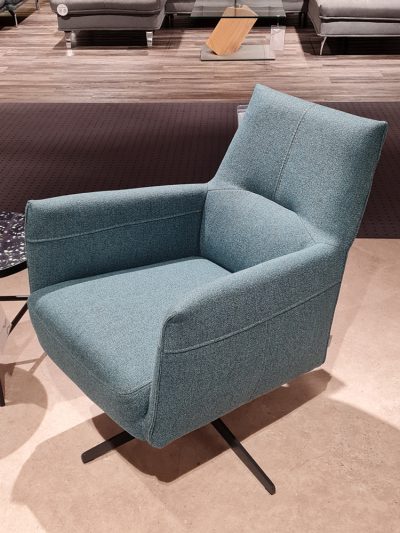 Der blaue Polstersessel von Möbel Gruber besticht durch ein modernes Design auf einem Drehfuß, perfekt für jeden hellen Boden.