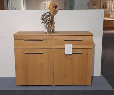Die Kommode von Möbel Gruber ist ein minimalistisches Sideboard aus Holz, das sich ideal zur Präsentation im Innenbereich eignet und mit einer kleinen Skulptur verziert ist.