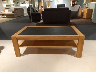 Der Couchtisch von Möbel Gruber verfügt über eine Glasplatte und eine untere Ablage und eignet sich ideal für die Präsentation im Wohnzimmer-Showroom.