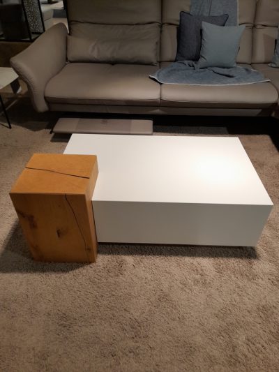 Modernes Wohnzimmer mit beigem Sofa, blauen Kissen und elegantem weißen Couchtisch aus Holz von Möbel Gruber.