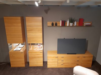 Modernes Wohnzimmer mit Musterring Wohnwand mit Schränken, Regalen, TV-Ständer, Pflanzen und Büchern von Möbel Gruber.