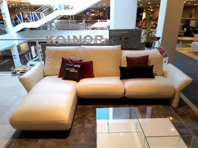 Koinor Polstergarnitur mit Kissen im Showroom von Möbel Gruber, im Vordergrund ein Couchtisch aus Glas.