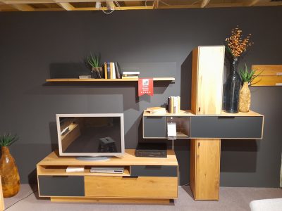 Modernes Wohnzimmer mit Interliving Wohnwand, TV-Ständer, Regalen und dekorativen Vasen vor einer dunklen Wand.