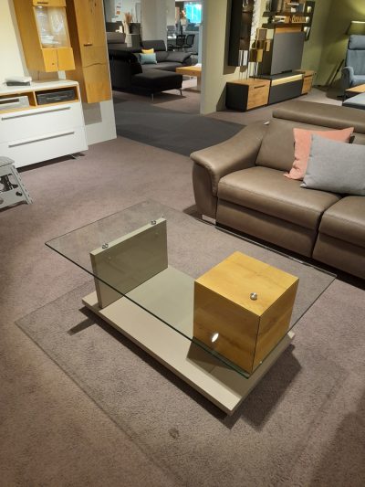Modernes Wohnzimmer von Möbel Gruber mit Interliving Couchtisch, braunem Ledersofa und Holzakzenten in einem Ausstellungsraum.