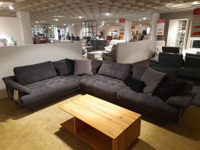 Polstergarnitur mit Kissen von Möbel Gruber, davor ein Couchtisch aus Holz auf einem beigen Teppich.