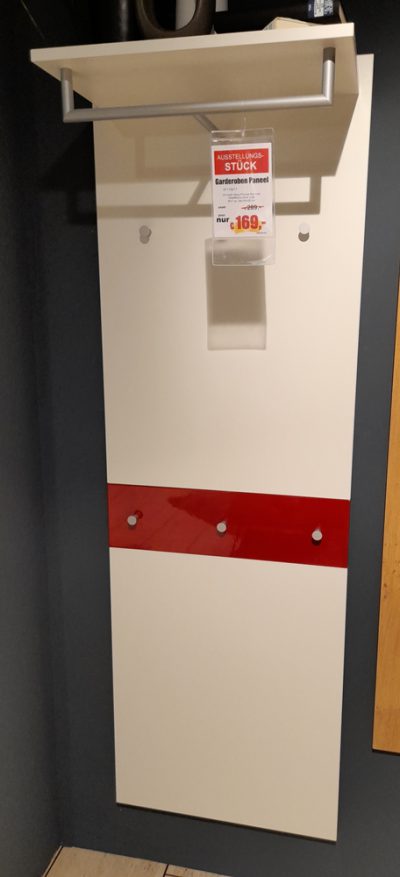 Garderobenpaneel von Möbel Gruber, mit roter Leiste und Haken, im Angebot für 169 Euro, hängt an einer grauen Wand.