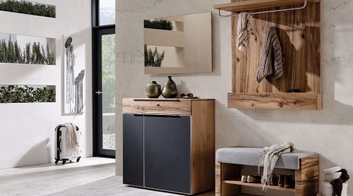 Moderner Eingangsbereich mit Holzmöbeln, Garderobe, Bank und Dekoartikeln von Möbel Gruber. Vertikale Fenster rücken Grün in den Vordergrund.