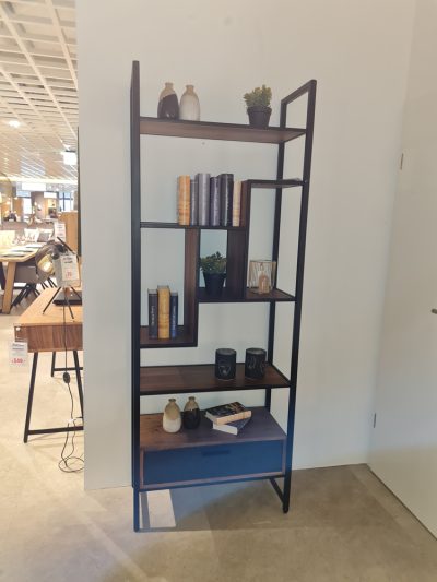 Das XOOON Bücherregal kombiniert Holzregale mit schwarzem Metall und präsentiert Bücher, Vasen, Kerzen und eine kleine Topfpflanze.