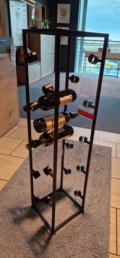 Das Flaschenregal von Möbel Gruber hält Flaschen elegant auf einem Teppichboden in einem modernen Raum.
