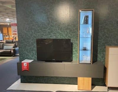 Moderne Wohnzimmereinrichtung mit einem Fernseher an einer Interliving Wohnwand und einer Glasvitrine mit Glaswaren daneben.