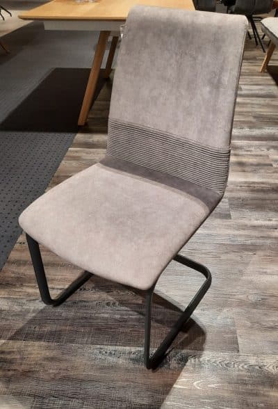 Der Interliving Schwingstuhl von Möbel Gruber besticht durch einen modernen Beige-Look mit einem eleganten schwarzen freitragenden Metallrahmen auf Holzboden.