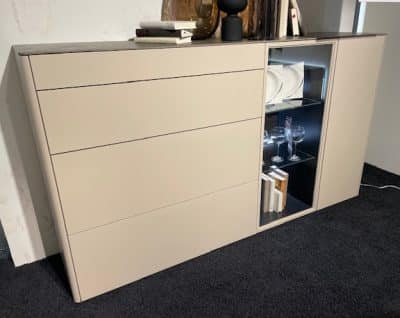 Minimalistisches beiges Sideboard mit drei Schubladen und einer Glasvitrine für Teller, Gläser und Bücher.