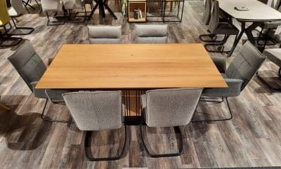 Eine Interliving-Tischgruppe mit sechs grau gepolsterten Stühlen steht elegant auf einem Holzboden.