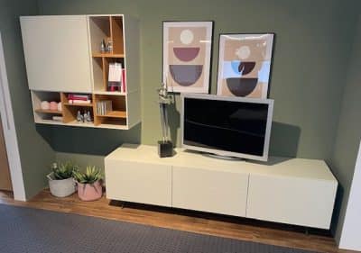 Modernes Wohnzimmer mit Flachbildfernseher, Wohnwand, abstrakter Kunst und Topfpflanzen auf Holzboden.