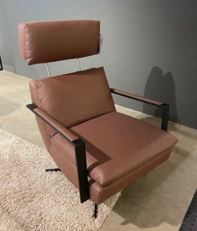 Relaxsessel von Möbel Gruber: brauner Leder-Relaxsessel mit hoher Rückenlehne und schwarzen Metallarmlehnen auf hellem Teppich.
