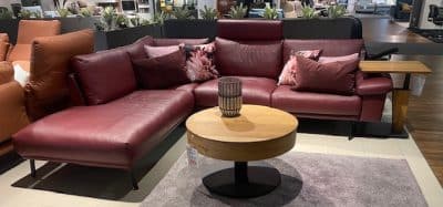 Modernes Wohnzimmer von Möbel Gruber mit Polstergarnitur, geblümten Kissen, hölzernem Couchtisch und grauem Teppich.