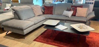 Im Showroom von Möbel Gruber sind die Interliving Polstergarnitur, ein schwarz-weißer Couchtisch und ein roter Teppich zu sehen.